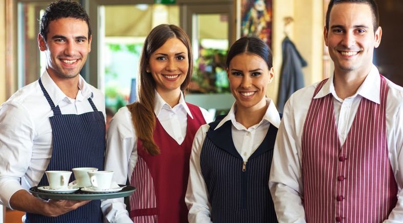 Vier Gastronomiearbeiter lächeln in die Kamera